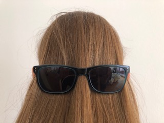 Mädchenkopf von hinten fotografiert mit aufgesetzer Sonnenbrille