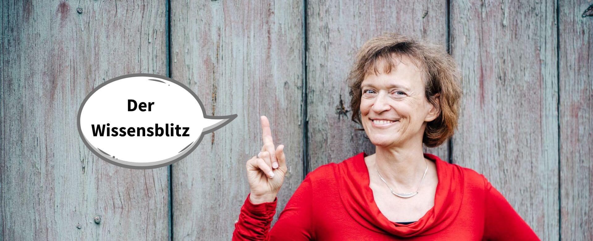 Eine lächelnde Frau mit Kopfhörer sitzt vor einem Laptop neben ihr ihr ein Schild "Der Wissensblitz" zu sehen. 